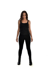 Fototapeta premium full length portrait of brunette girl wearing black singlet, jeans jeans and boots. standing pose, isolated on white studio background.