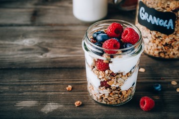 Healthy blueberry and raspberry parfait with greek yogurt in glass mason jar on wood background