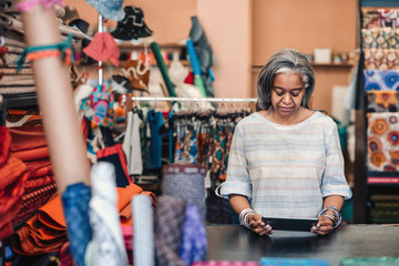Fototapeta na wymiar Mature woman using a digital tablet in her fabric store