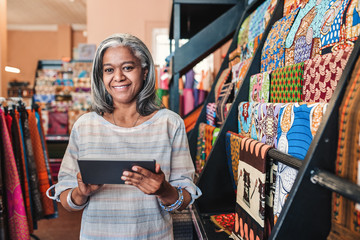 Smiling woman using a digital tablet in her textiles shop 