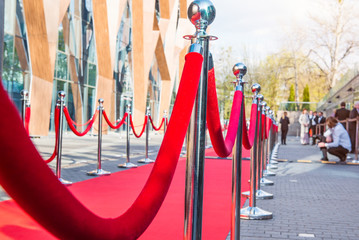 Close up red carpet ceremony with selective focus on the stanchions and the ropes with blurred...