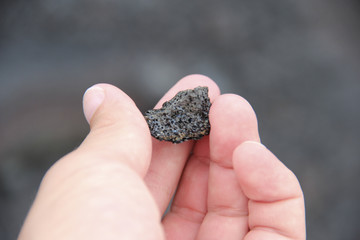 Close up of hand holding iridescent lava rock