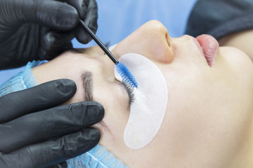 Woman on the procedure for eyelash extensions, eyelashes lamination. 