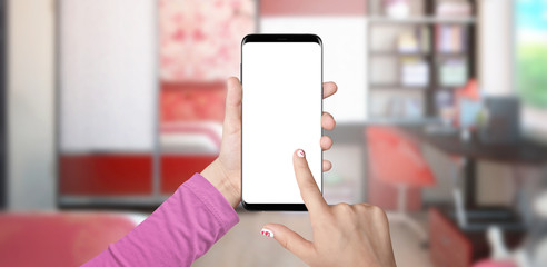 Little girl holding modern black smartphone with isolated screen in vertical position, living room in background
