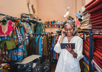 Smiling woman talking on a phone in her fabric store