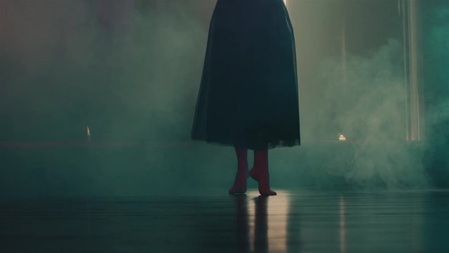 close up shot of the elegant legs of a woman who dances, the lady dances on the floor barefoot, the woman is engaged in ballet in the studio