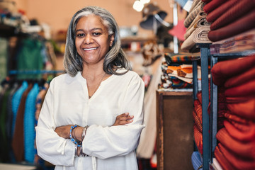 Fototapeta na wymiar Smiling mature woman standing in her colorful fabric shop