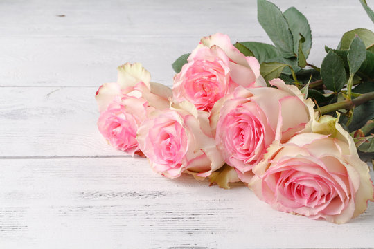 Beautiful pink roses lbouquet lying on a wooden table