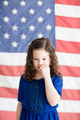 Little girl standing in front of an American flag background