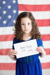 Little girl holding sign with American flag background