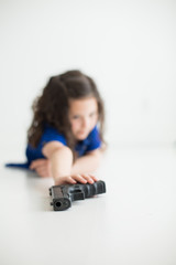 Child reaching for hand gun in white room