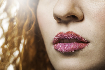 Close up of a woman's lips with pink lipstick and sugar