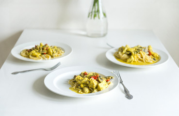 3 plates with pasta with chicken fillet, mushrooms and pepper in cream sauce on the dining table