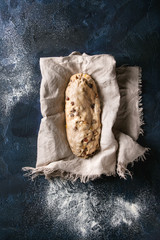 Christmas cake, traditional German festive baking. Wholegrain dough stollen preparation on linen napkin over dark blue texture background. Top view, space