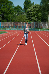 Fototapeta premium Sports woman running track and field running on a treadmill at the stadium on a sunny morning in the summer