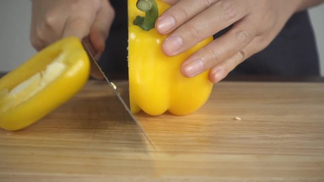 Slow motion - Close up of woman making healthy food and chopping bell pepper on cutting board in the kitchen.