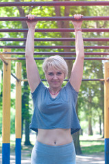 Obraz premium Young woman is engaged in fitness on a sports field in a park in the summer on a sunny day