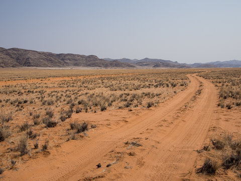 Empty tire track dirt road in Namib desert with mountains, Damaraland, Namibia, Southern Africa