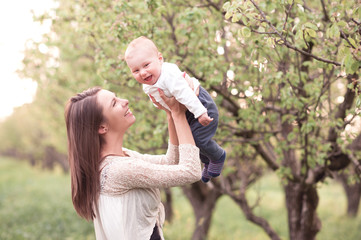 Fototapeta premium Smiling woman holding baby outdoors. Happiness. Motherhood.