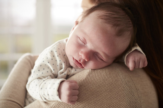 Close Up Of Sleeping Newborn Baby Sleeping On Mothers Shoulder