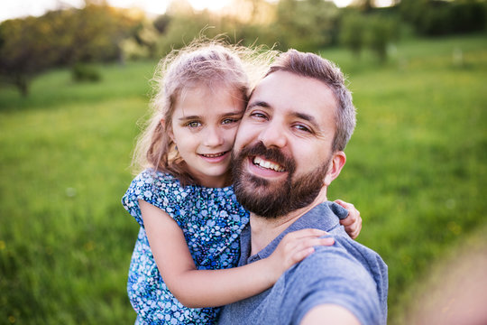Father with a small daughter having fun in spring nature, taking selfie.