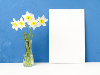 Bouquet of fresh flowers, canvas on white table, opposite blue textured concrete wall. Empty space for text.