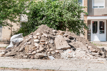 Big pile of cement concrete and dirt on the street in front of the residential building left as...