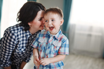 Mother and son in plaid shirts smile, hug and kiss. The concept of a happy family and carefree...