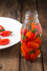 red tomatoes in bottle glass on wood


