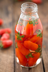 red tomatoes in bottle glass on wood

