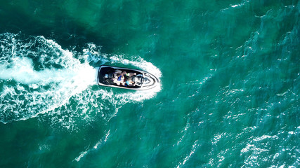 Aerial bird's eye view of jet ski cruising in high speed in turquoise clear water sea