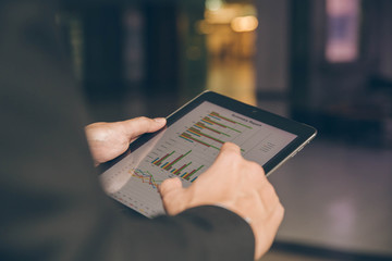 Close up businessman hand using tablet and pointing on summary report at office.Male businessman reviews a summary report on tablet.
