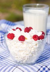 Milk and glass bowl with soft cheese and raspberry in summer