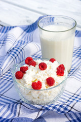Milk and glass bowl with soft cheese and raspberry in summer