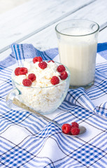 Milk and glass bowl with soft cheese and raspberry in summer