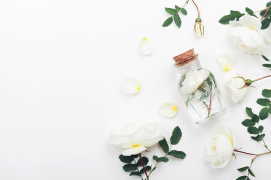 Glass jar with aroma water and white rose flowers for spa and aromatherapy. Top view and flat lay style.