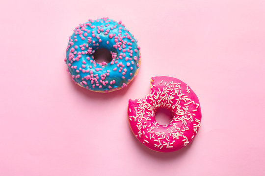 Delicious glazed doughnuts on color background, top view