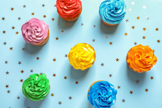 Flat lay composition with colorful birthday cupcakes on color background