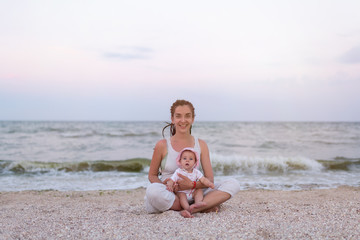 Fototapeta na wymiar Happy family mother and child daughter doing yoga, meditate in lotus position on beach at sunset