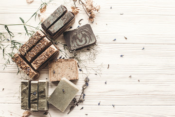 natural soap. handmade herbal soap with wildflowers, healing flowers, mint,  lavender, space text. eco natural product for skin care. soap on white rustic background with dried herbs, flat lay.