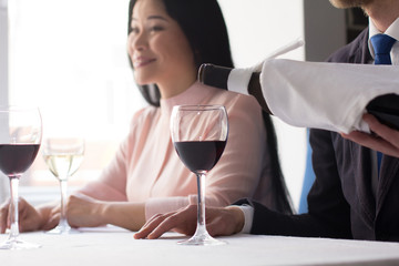 Waiter serving wine to business partners at restaurant before lunch.