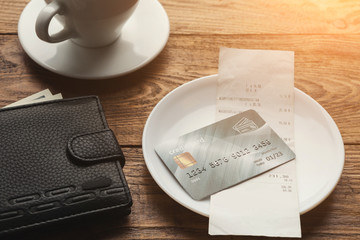Restaurant bill and credit card on wooden table