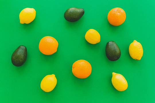 oranges, avocado and lemons on bright green paper trendy background, flat lay. modern summer image concept. multi fruit flat lay, juicy vitamin abstract background, pop art