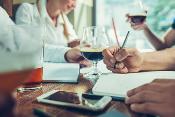 Young cheerful people smile and gesture while relaxing in pub.