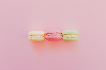 stylish colorful macaroons on trendy pink paper, flat lay. space for text. modern food photography concept. tasty pink, yellow, green macarons, yummy background