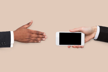 Businessman offering blank smartphone to partner