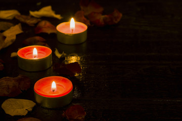 Lighted candle on the background of a large number of wilted leaves