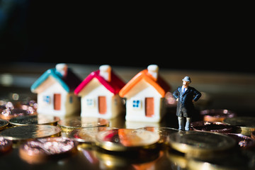Miniature people, old man standing with colorful house and golden stack coins using as business concept - Vintage filter