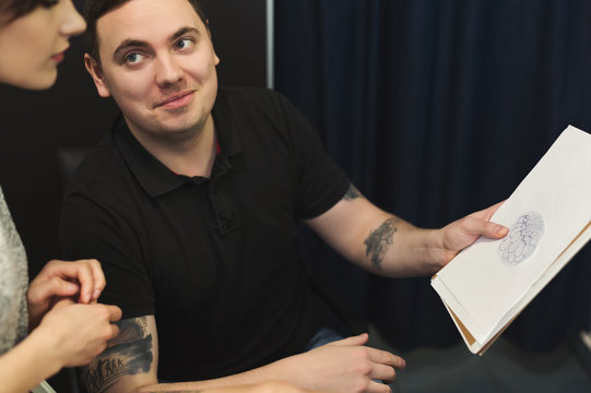Man and woman choosing tattoo design in studio