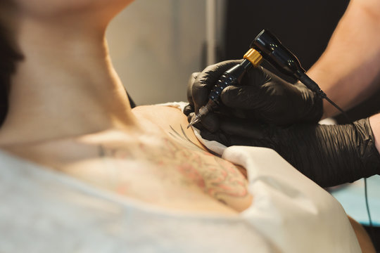 Tattoo artist working with needle on clients body